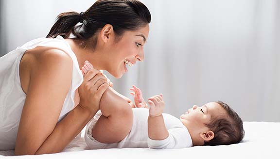 Cheerful mother playing with her baby