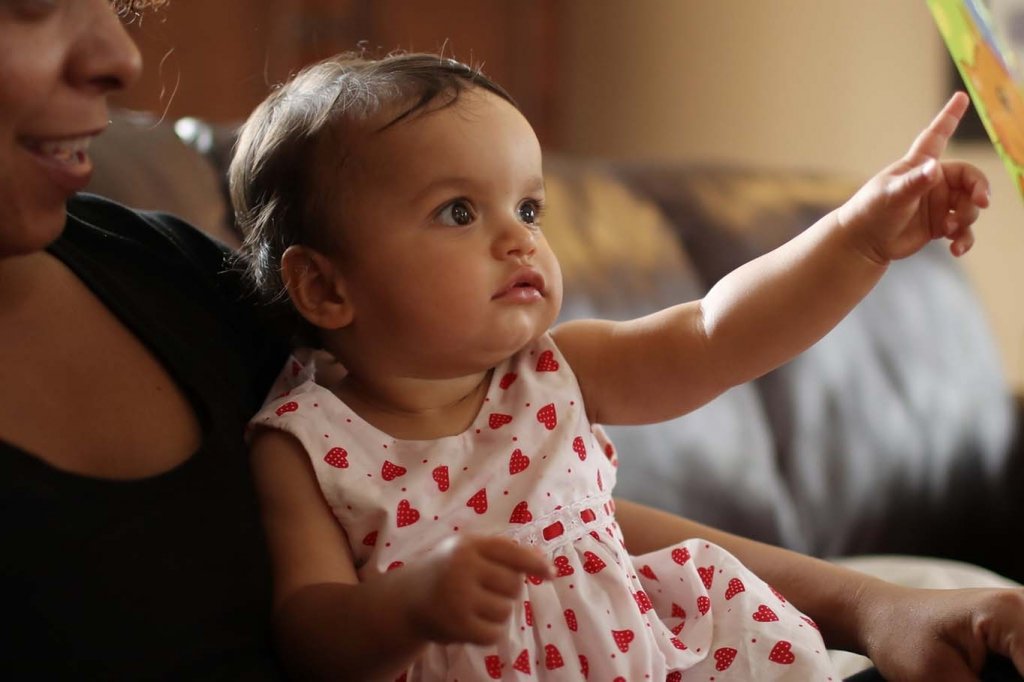 Baby girl reading a book with mom