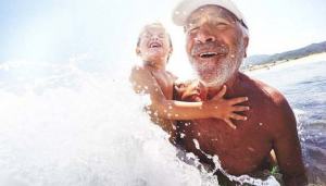 Photo of smiling grandfather and his little grandson having fun bathing in the sea